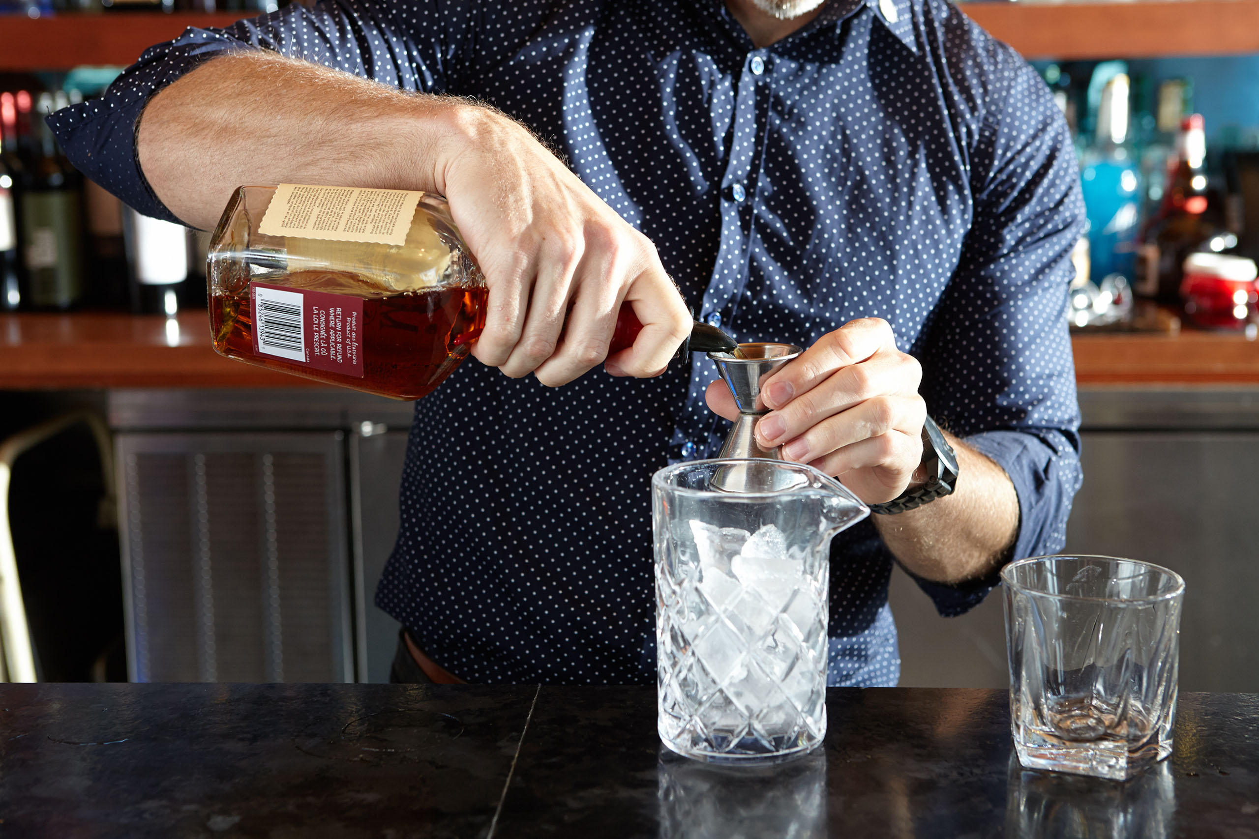 Undistinguishable man pouring alcohol into a mixing glass for a cocktail